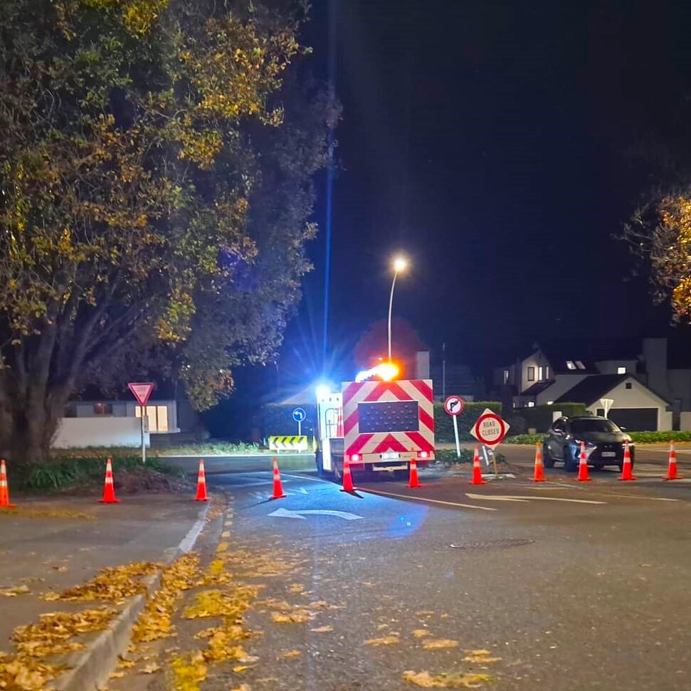 a closed road at night with road cones and a traffic control truck